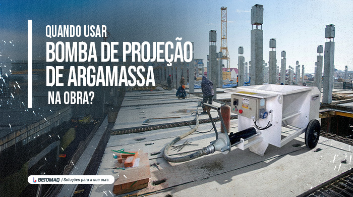 Equipamento de projeção de argamassa em obra, com estrutura em construção e trabalhadores ao fundo.